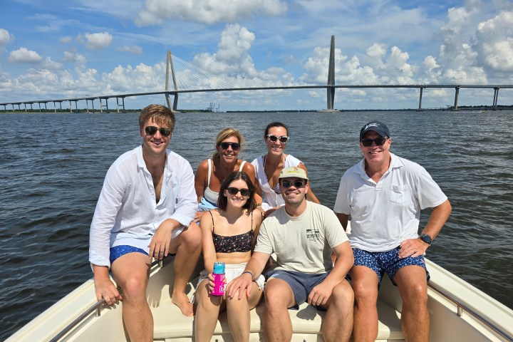 Group of six people on a boat with a large suspension bridge in the background.