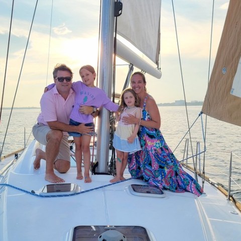 a man standing in front of a boat next to a body of water