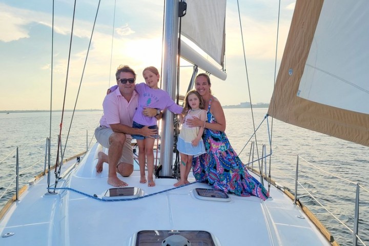 a man standing in front of a boat next to a body of water