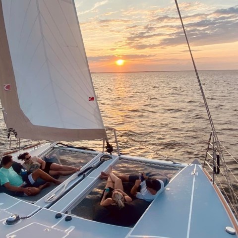 People relaxing on a sailing boat at sunset with calm sea.