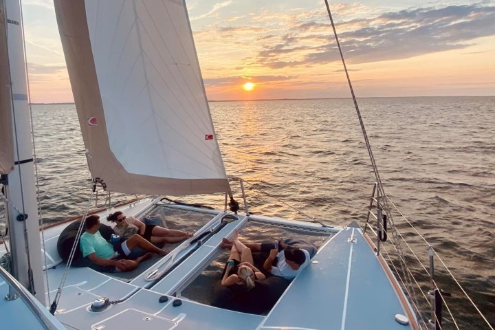 People relaxing on a sailing boat at sunset with calm sea.