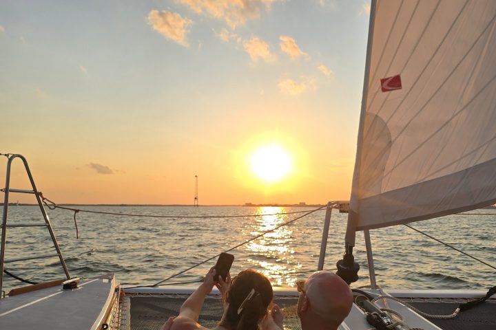 Two people on a boat watching a sunset over the ocean.