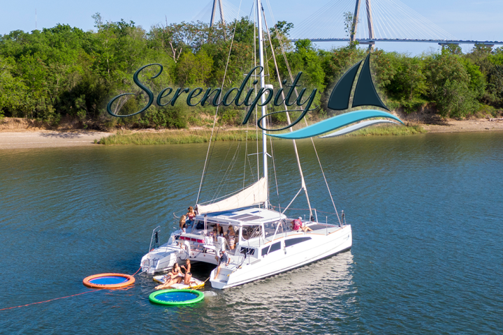 Catamaran on river with people on deck, trees in background, text overlay 'Serendipity' with a boat logo.