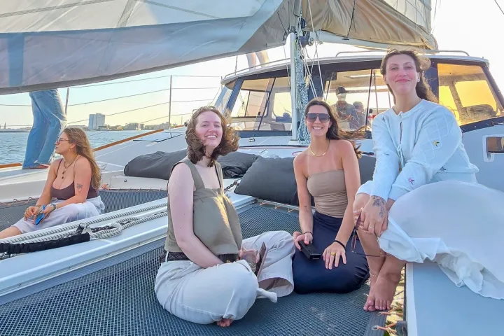 People sitting on a sailboat deck smiling at sunset.